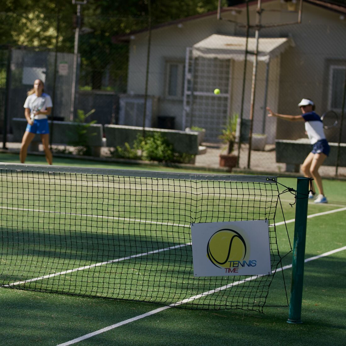 Lezione a due, il cartello Tennis Time appeso alla rete